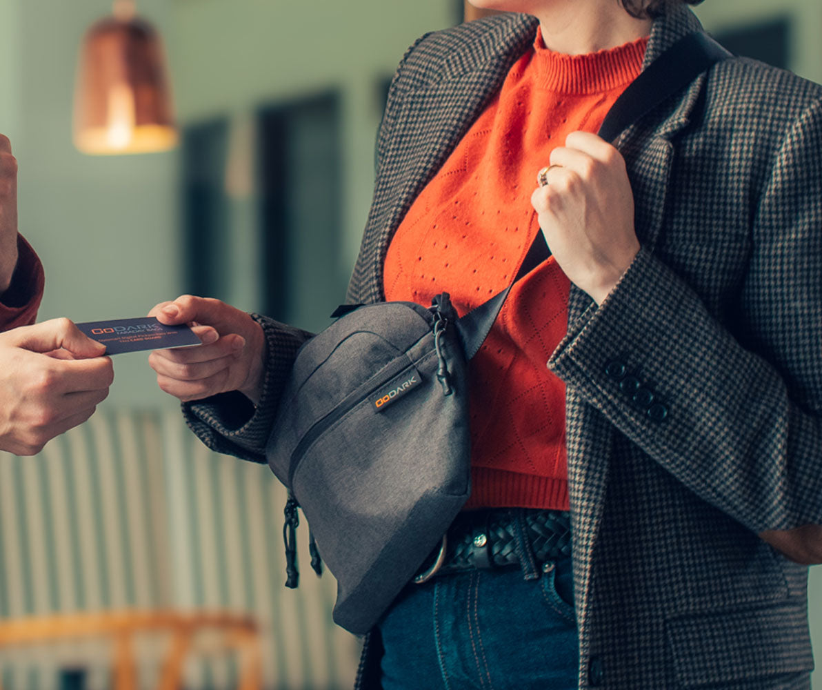 Person holding a GoDark Crossbody Bag with a blurred indoor background
