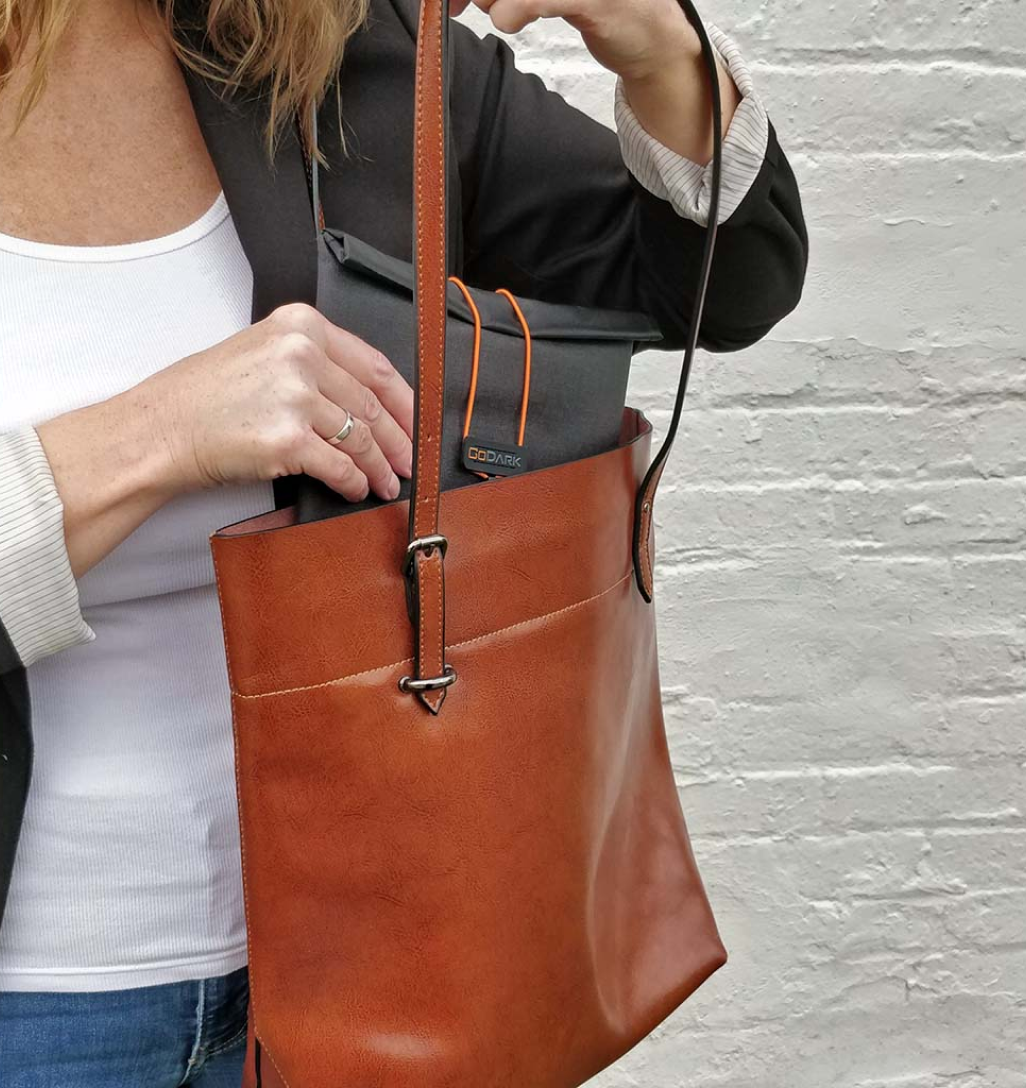 Woman putting the GoDark Tablet size bag into her hand bag