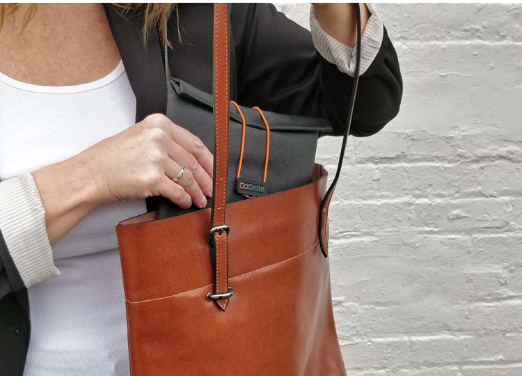 Woman putting the GoDark Tablet size bag into her hand bag